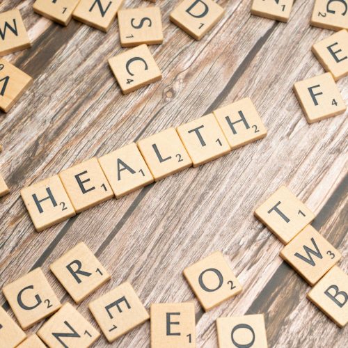 Scrabble tiles spelling 'HEALTH' on wooden surface, symbolizing wellness.